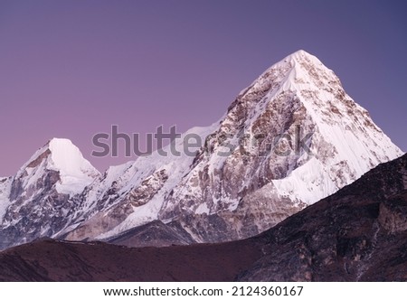 snow peak behind edge of mountain and pink purple sky above it in Nepal