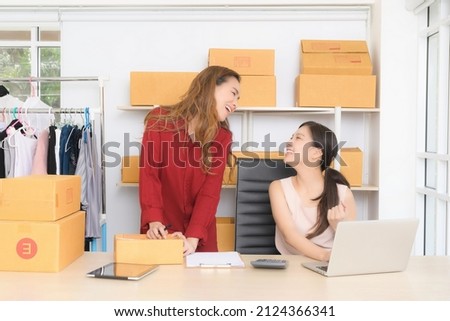 Two young business women are happily discussing online marketing plans in their home office.