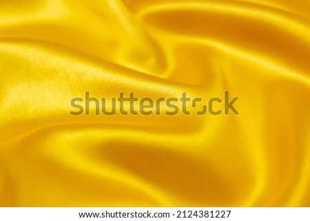 Mauled gold-colored glossy fabric texture background. This fabric is made of 100% polyester. Royalty-Free Stock Photo #2124381227