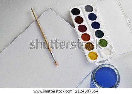 watercolor paints brush jar with water and sketchbook on a white background. High quality photo