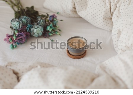 Good morning, Flat lay composition with coffee cup, blue flowers and warm blanket in cozy bed, top view.