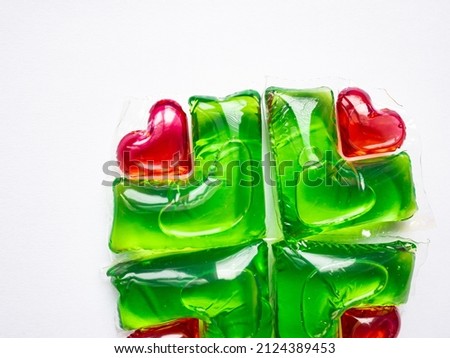 Washing capsules on a white background. Liquid laundry detergent in red-green heart-shaped capsules.