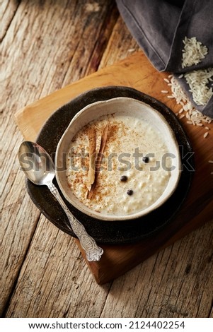 Arroz con leche with cinnamon, a typical Ecuadorian dessert served on a white and black plate with a rustic, warm and traditional atmosphere