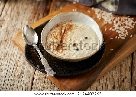 Arroz con leche with cinnamon, a typical Ecuadorian dessert served on a white and black plate with a rustic, warm and traditional atmosphere.  Royalty-Free Stock Photo #2124402263
