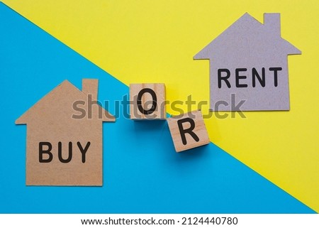 Buy or sell text on paper house model and wooden block with colored paper background. Property investment and business concept.