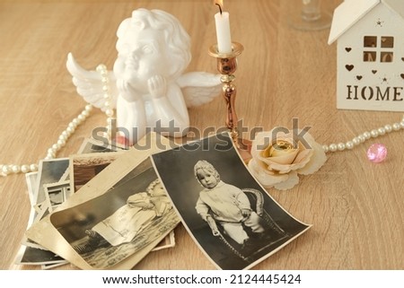 stack of vintage photos on table, romantic still life in love style, cupid with wings, candles burning, concept of family tree, genealogy, childhood memories