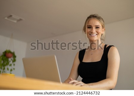 Young woman working at home in her kitchen with laptop and papers on kitchen wooden desk. Home office concept. Gray notebook for working. Home office concept. High quality photo