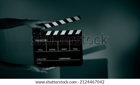 Blurry images of movie slate or clapper board. Hand holds empty film making clapperboard on color background in studio for film movie shooting or recording. 
