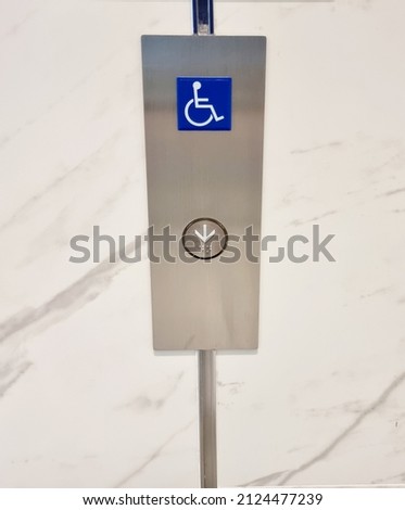 A elevator button with handicapped sign on it.