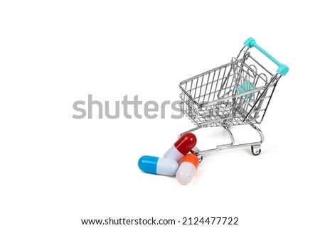 Shopping cart and pills isolated on white background. Three multi-colored capsules. Medico-pharmaceutical concept. Copy space. Royalty-Free Stock Photo #2124477722