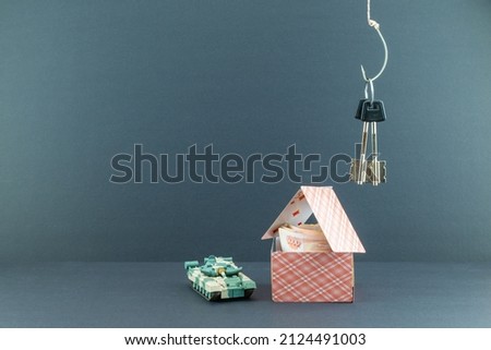 the keys are hanging on a hook above the card house where the money is. a guard in the form of a toy tank. background picture.