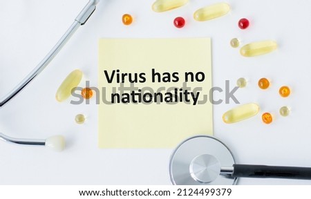 text Virus has no nationality on a yellow sticker on a white background next to a stethoscope and loose tablets