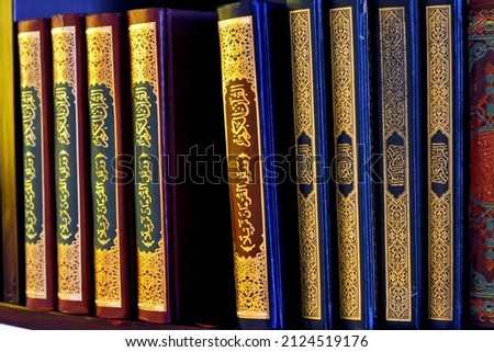 Holy Quran books in a row standing on a wooden shelf inside a mosque, English translation of the Arabic Text (The Holy Noble Quran), it's the central religious text of Islam, revelation from God Allah