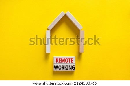 Remote working symbol. Concept words 'Remote working' on wooden blocks near miniature wooden house. Beautiful yellow background. Business, remote working concept.