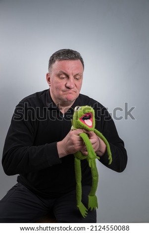 A man squeezes a green frog soft toy with his hand.
