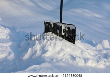 Snow shovel isolated in deep snowdrift picture after snowfall and winter storm on a sunny day