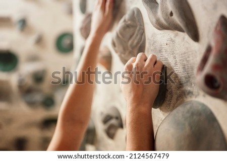 Climber wearing in climbing equipment. Practicing rock-climbing on a rock wall indoors. Xtreme sports and bouldering concept. Royalty-Free Stock Photo #2124567479