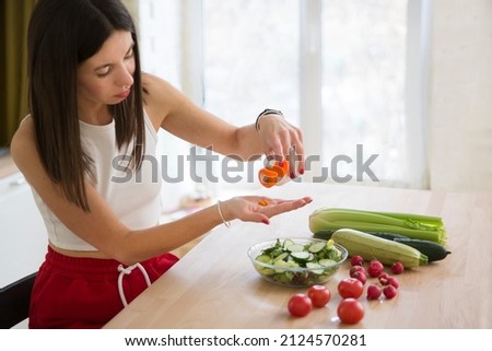 healthy lifestyle. Supporting immune system. woman takes vitamins. vitamin supplements for beauty, skin, hair, with green vegan food. at lunch at home Royalty-Free Stock Photo #2124570281