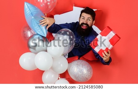 Birthday party. Smiling bearded man with balloons holds gift. Happy holiday celebration, anniversary.