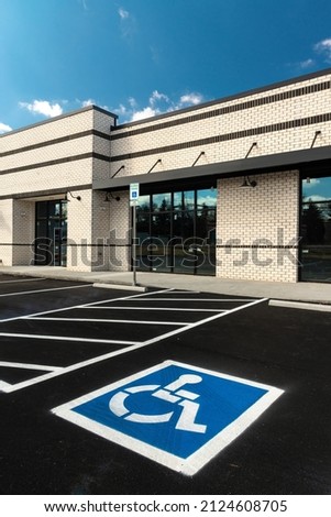 Vertical shot of a handicapped parking sign painted in a handicapped parking spot at a new retail strip shopping center under construction.