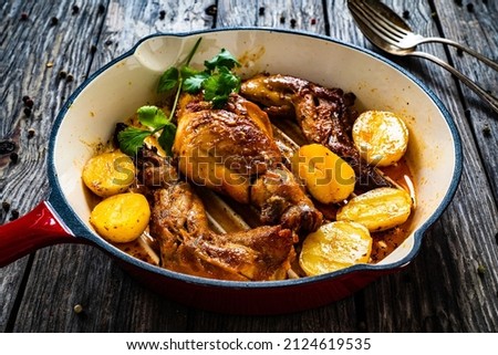 Cooked rabbit thighs with potatoes in frying pan