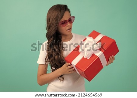 serious kid with present box. teen girl giving birthday gift. child in sunglasses sharing box