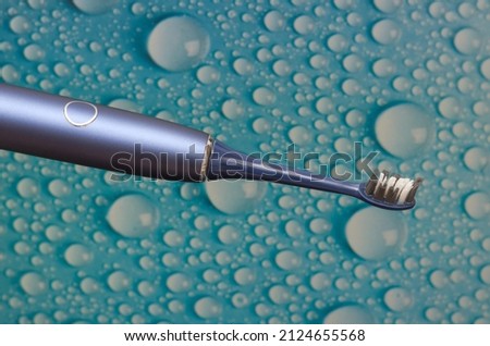 sonic electric toothbrush on background with water drops