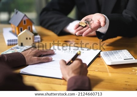 The real estate buyer and broker agree to sign the contract and hand over the house keys.