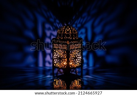 Black lantern with reflection from blue background for the Muslim feast of the holy month of Ramadan Kareem.