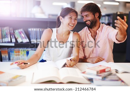 Two student friends taking the picture to them self sitting in the library, teenagers taking selfie with telephone camera, learning funny at university, happy young people taking picture smiling