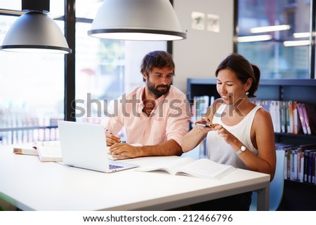 Couple of colleagues working in office, asian woman taking picture with smartphone of some information from the book, businesspeople working with computer and telephone, technology and businesspeople