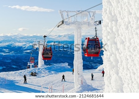 Ski resort in sunny day. Red cable car in a ski resort in the Alps. red gondola funicular in a ski resort in sweden on a frosty sunny day Royalty-Free Stock Photo #2124681644