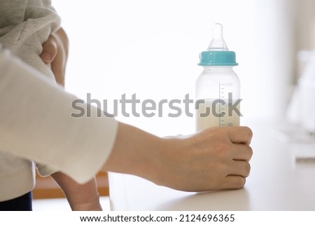 Asian female giving milk to her baby Royalty-Free Stock Photo #2124696365