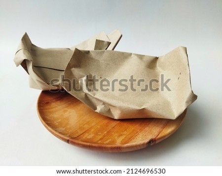 the way of wrapping traditional food that bought from Indonesian traditional market, using brown paper warp on isolated white background Royalty-Free Stock Photo #2124696530