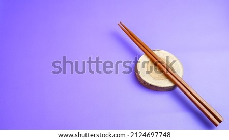 Wooden kitchenware that gives a classic and minimalist impression. Food and drink concept. Food Photography. Flat Lay, Wooden Chopsticks on the table. Space for text. Purple Background.
