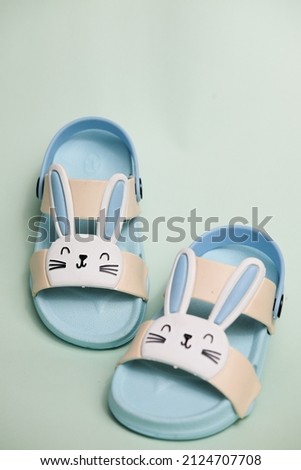 blue children's shoes, with a bunny character, on a plain green background for a photo illustration of a shoe product