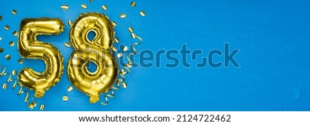 golden foil balloon number fifty eight. Birthday or anniversary card with the inscription 58. blue concrete background. Anniversary celebration. Banner. copy space Royalty-Free Stock Photo #2124722462