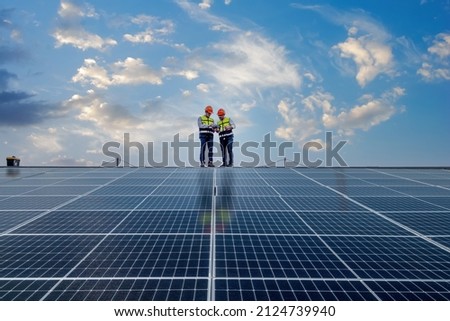 Engineers walking on roof inspect and check solar cell panel by hold equipment box and radio communication ,solar cell is smart grid ecology energy sunlight alternative power factory concept. Royalty-Free Stock Photo #2124739940