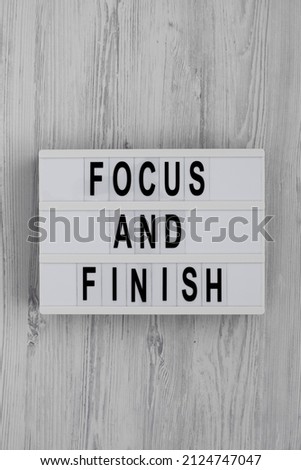 'Focus and Finish' on a lightbox on a white wooden surface, top view. Flat lay, overhead, from above. 