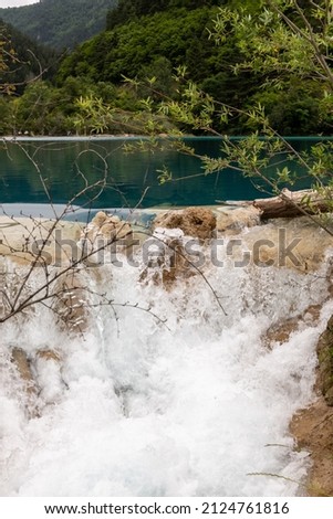 Vertical image of the turquoise blue waters of Jiuzhaigou Valley Scenic Area Lake running down the cliff, Sichuan, China 