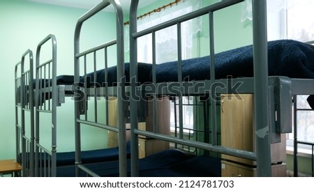 Empty duvet-covered beds in an army barracks Royalty-Free Stock Photo #2124781703