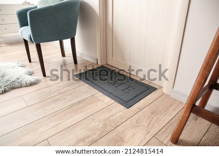 Black mat near light wooden door in modern hall Royalty-Free Stock Photo #2124815414