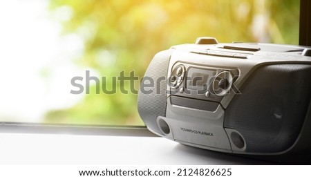 Cassette and CD player in 1990 style on window with natural blurred background. 1990’s vintage life style concept. Royalty-Free Stock Photo #2124826625