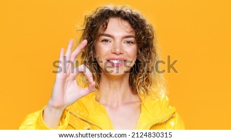 Okay Sign Young Woman Shows Emotions, well, gesturing with her hands Smiling showing her fingers in front of camera with delight and admiration on yellow background. Fashion. Monotone Positive emotion