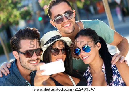 Outdoor portrait of group friends taking photos with a smartphone.