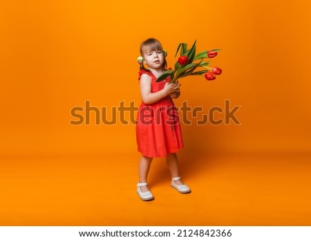 cute little blonde girl with a bouquet of tulips in a cotton dress on a yellow background. March 8