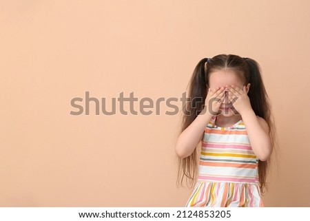 Crying little girl on beige background