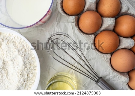 milk, eggs, flour vegetable oil and a whisk