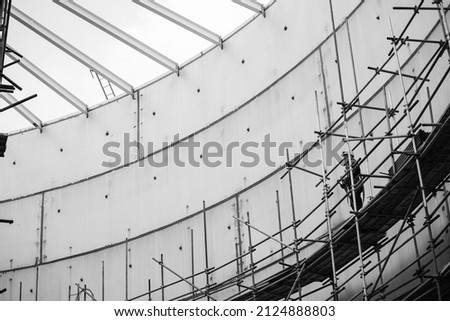 Picture monochrome Worker male assembly in progress storage tank oil inspection scaffolding work at high in confined space.
