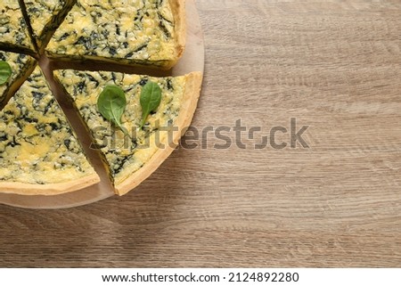 Cut delicious spinach pie on wooden table, top view. Space for text
